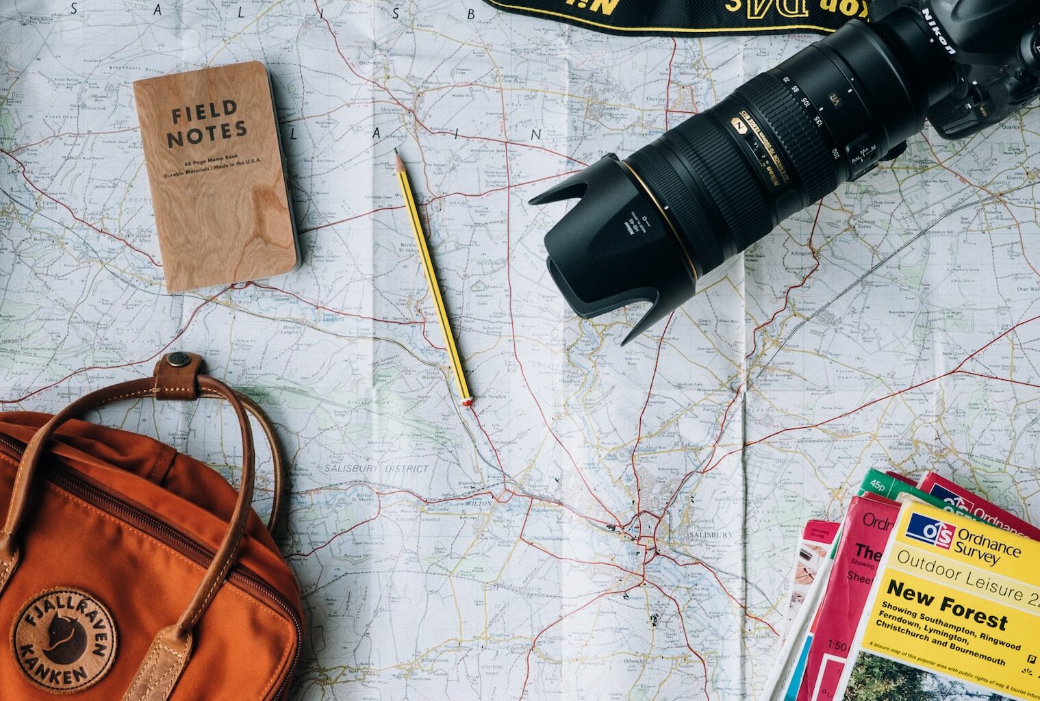 flat lay photography of camera, book, and bag